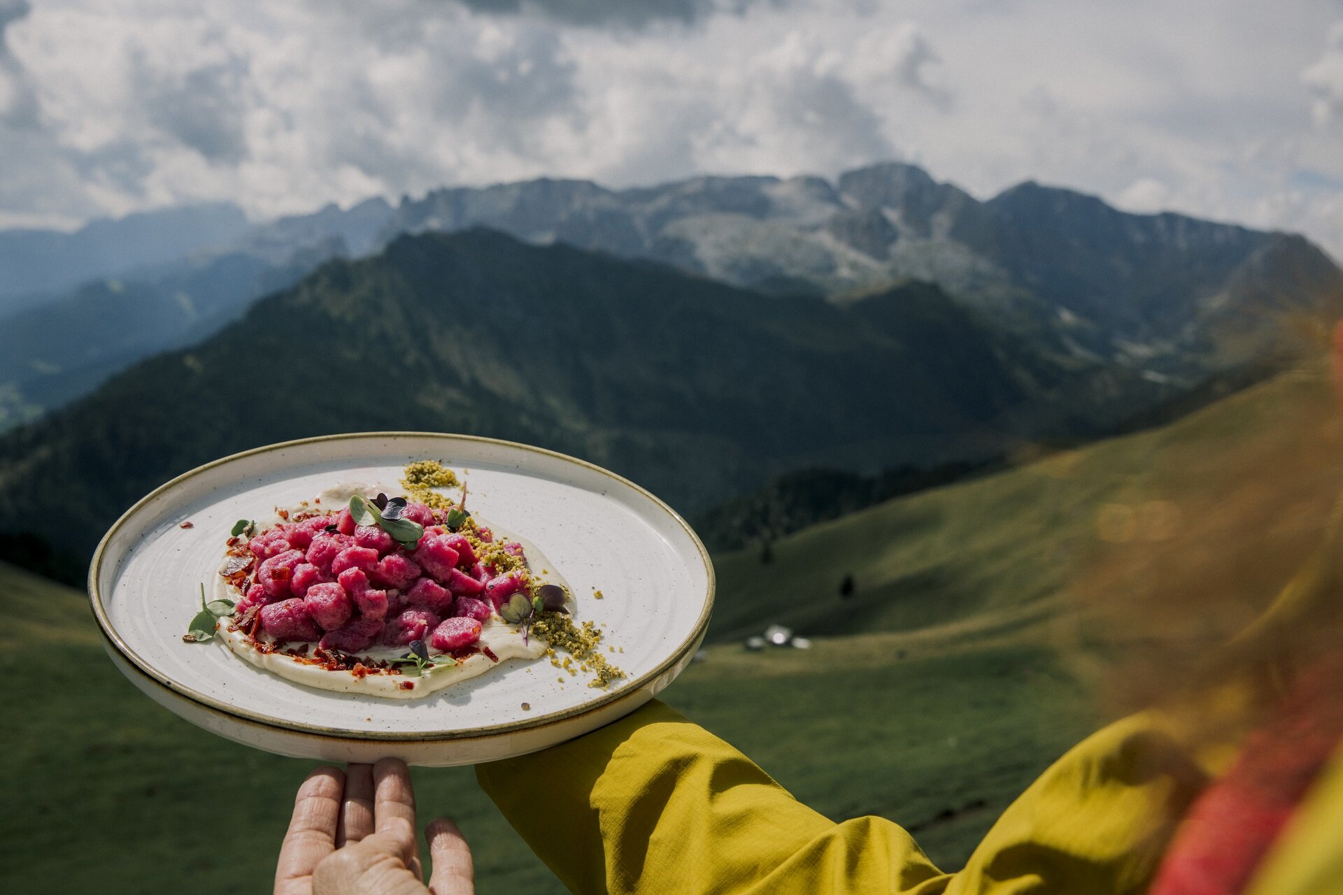Piatto di gnocchi rosa da un rifugio con panorama delle Dolomiti di fassa  | © Federico Modica - Archivio Immagini ApT Val di Fassa