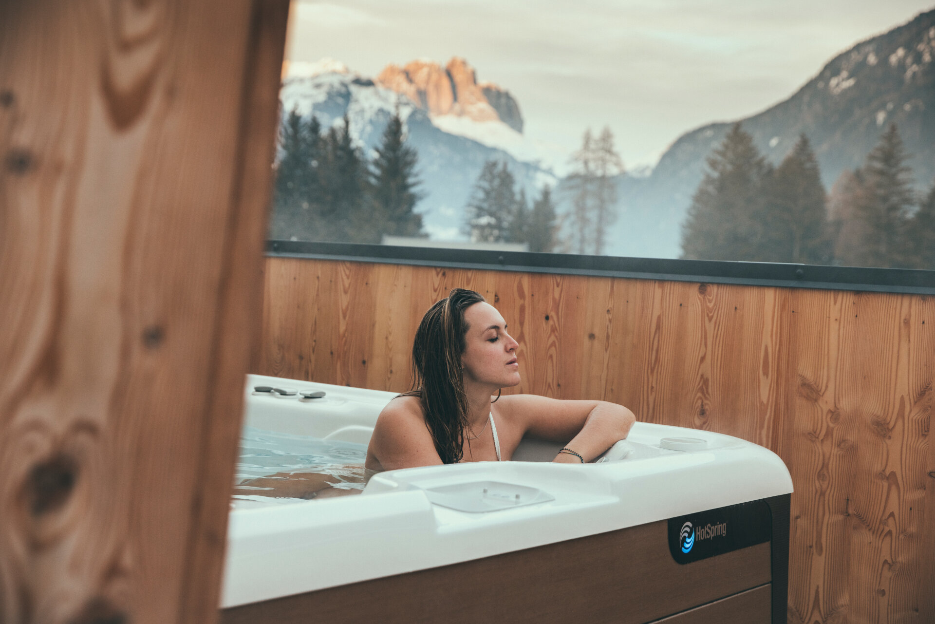 Persona nella vasca idromassaggio esterna con vista sulle Dolomiti innevate in Val di Fassa | © Federico Modica - Archivio Immagini ApT Val di Fassa