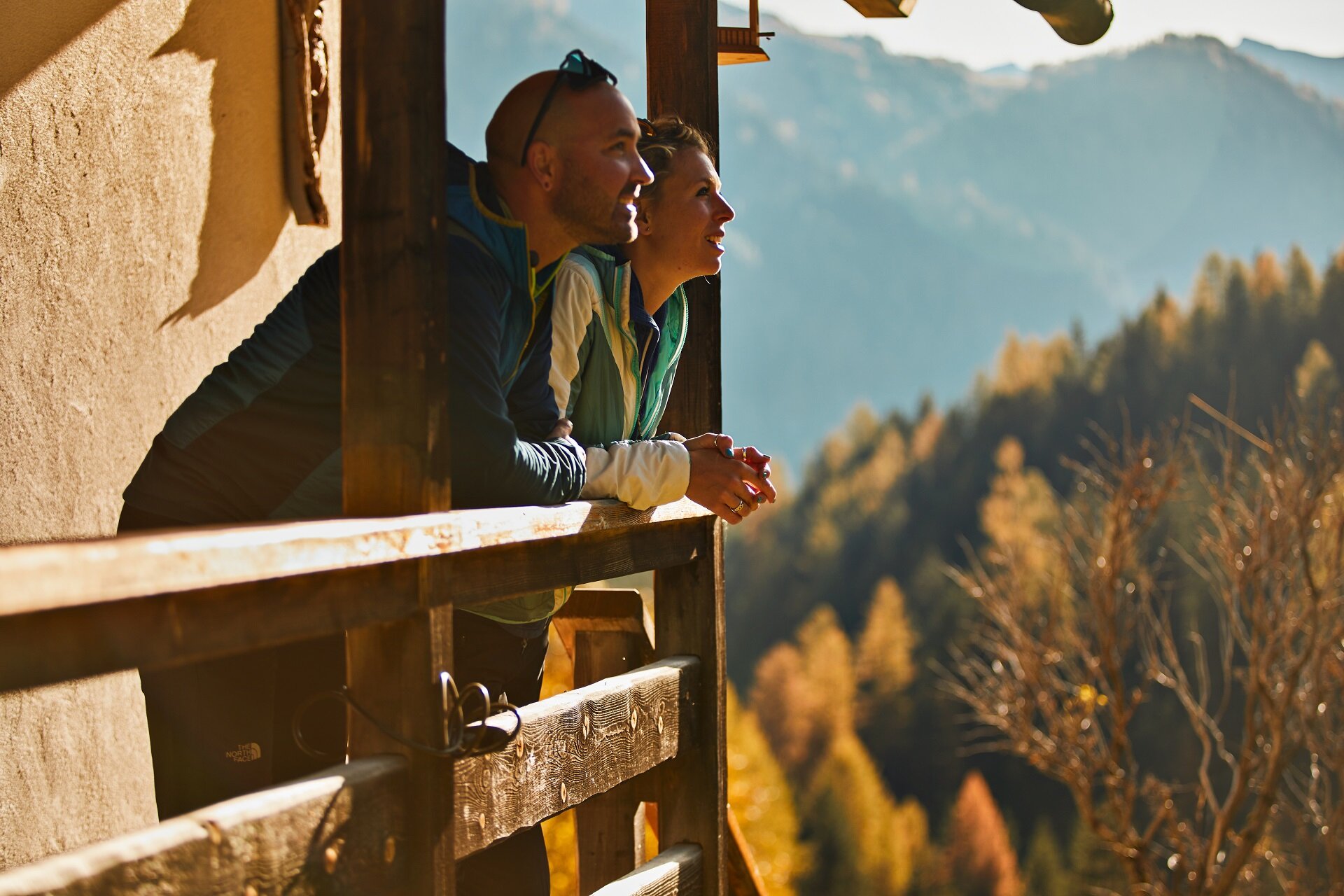 Persone che ammirano il paesaggio autunnale da un balcone in legno in Val di Fassa | © Fulvio Maiani Coolpixel - Archivio Immagini APT Val di Fassa